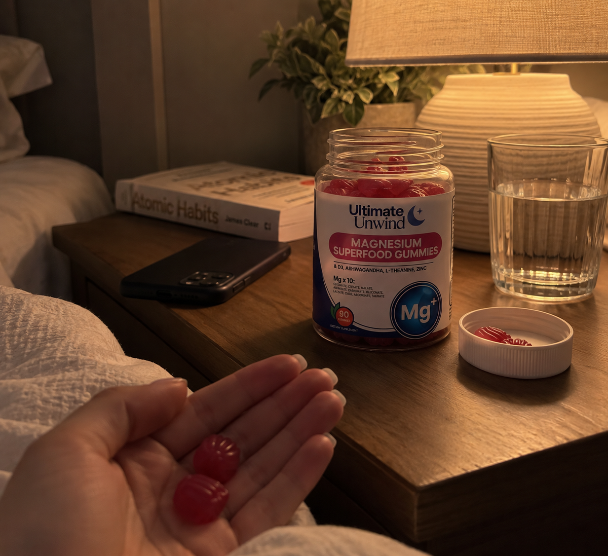 A bottle of Ultimate Unwind magnesium gummies on a bedside table in warm evening lamp light